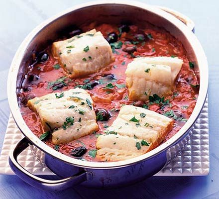 Peixe cozido com azeitonas pretas e tomates.